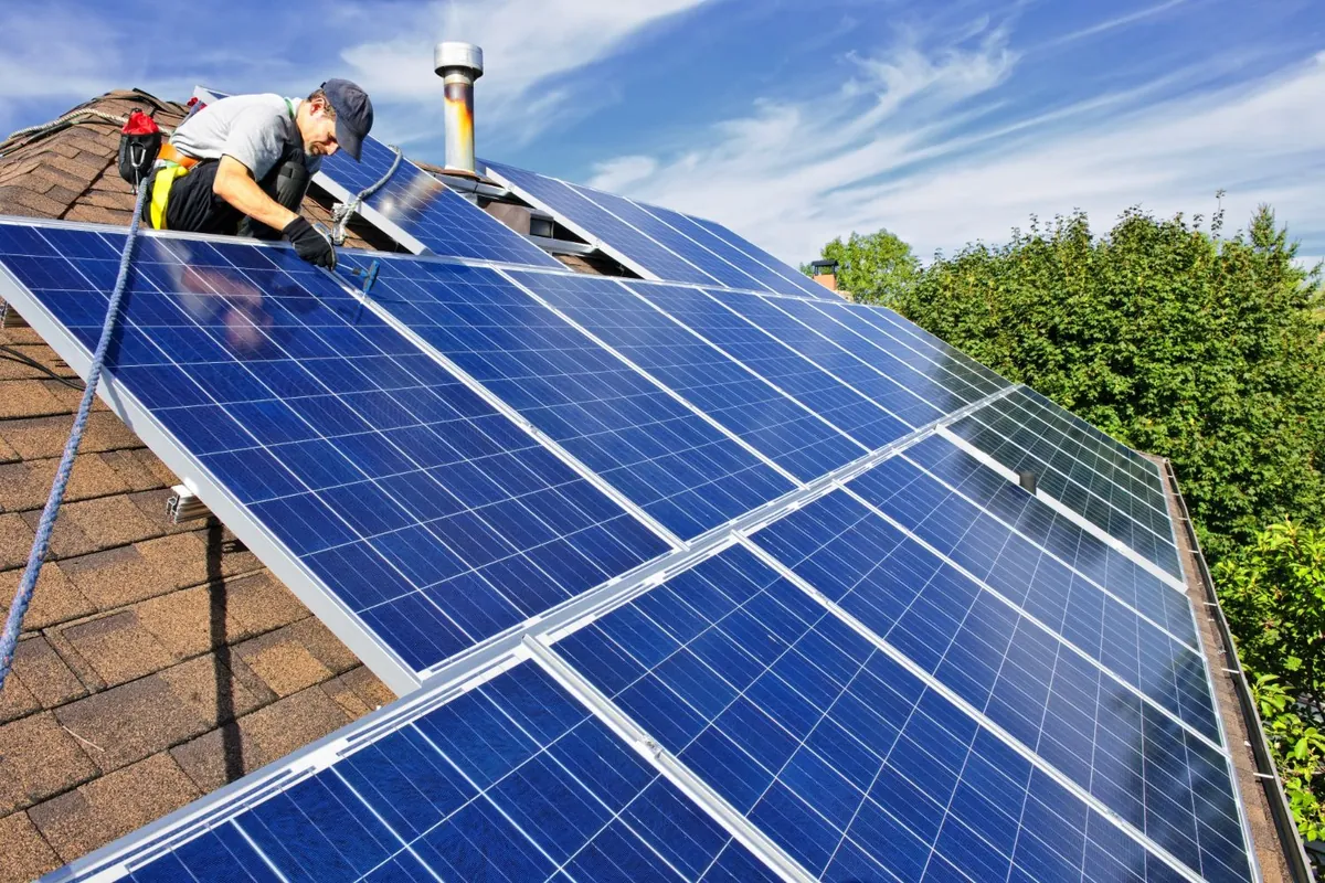 Monteur met valbeveiliging monteert zonnepanelen op een schuin dak